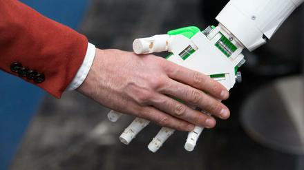 Ein humanoider Roboter gibt einem Menschen die Hand am Stand von ioX Lab bei der IT-Messe CeBIT.
