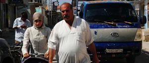 Menschen gehen im syrischen Al-Jiza vor einem Auto auf der Straße.