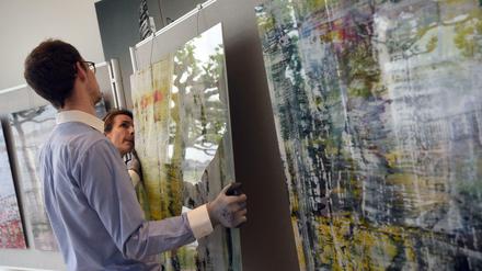 Mitarbeiter hängen Bilder von Gerhard Richter auf, die der Maler spendet, um ein Projekt gegen Wohnungslosigkeit zu unterstützen.