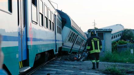 Ein Feuerwehrmann geht neben einem entgleistem Zug entlang.