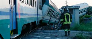 Ein Feuerwehrmann geht neben einem entgleistem Zug entlang.