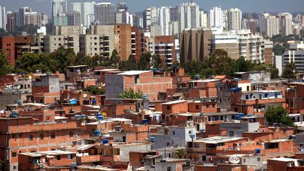 Vorne eine "planlose" Favela, hinten Hochhäuser in Sao Paulo. Können Wohngebiete nach den Regeln einer Favela besser geplant werden?