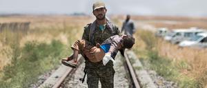 Ein kurdischer Kämpfer trägt ein verletztes Kind in Nordsyrien. Der Konflikt mit dem IS war einer der Gründe dafür, dass die Welt im vergangenen Jahr deutlich kriegerischer geworden ist.