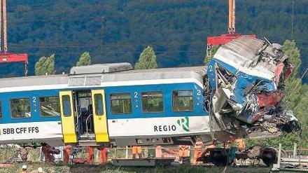 Aufräumarbeiten. Angestellte der Bundesbahn transportieren in Granges-pres-Marnand im Westen der Schweiz das Zugwrack ab, damit es in der Werkstatt zerlegt werden kann. Foto: dpa