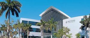 Vor einem modernen Gebäudekomplex stehen Palmen.