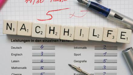 Auf einem Zeugnisformular mit schlechten Noten ist das Wort Nachhilfe mit Buchstabenplättchen aufgereiht.