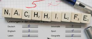 Auf einem Zeugnisformular mit schlechten Noten ist das Wort Nachhilfe mit Buchstabenplättchen aufgereiht.