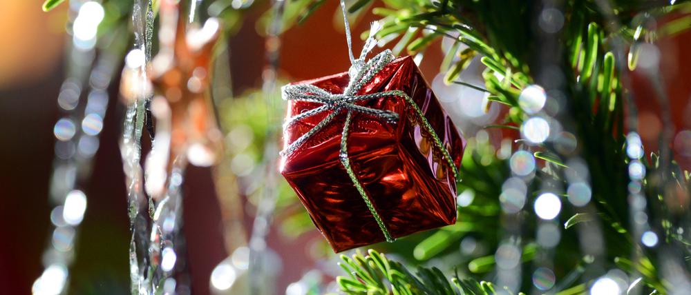 Ein kleines rotes Geschenkpaket als Weihnachtsbaumanhänger und Lametta
