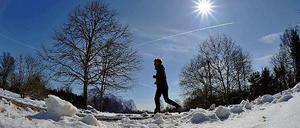 Jetzt auch im Sonnenschein. Ein Läufer joggt in Berlin durch den Schnee.