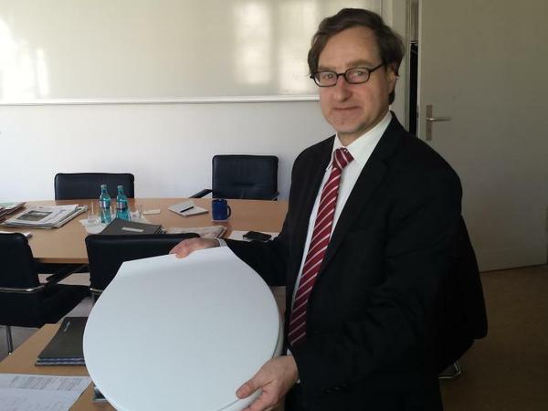 Immobilienstadtrat Michael Karnetzki posiert mit einem Geschenk der Paulsen-Schüler: dem angeblichen letzten heilen Klodeckel des Gymnasiums.