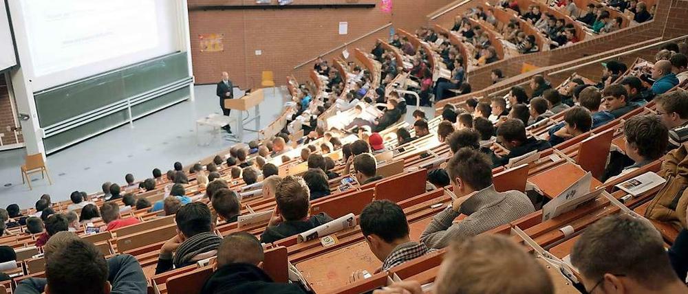 Studierende sitzen im Hörsaal, am Pult steht ein Professor.