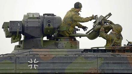 Ein Panzergrenadier reicht dem Kommandant eines Schützenpanzers eine Startvorrichtung für eine Panzerabwehrwaffe vom Typ "Milan".  