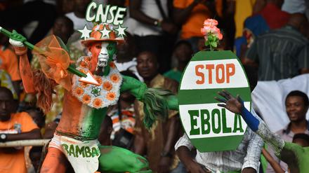 Ein Anhänger der Nationalelf der Elfenbeinküste hält ein Schild, um für einen stärkeren Kampf gegen die Ebola zu demonstrieren.