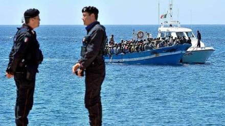 Ein Boot mit Flüchtlingen aus Nordafrika nähert sich der italienischen Küste und wird von einem Patrouillenboot der Küstenwache in den Hafen geschleppt.