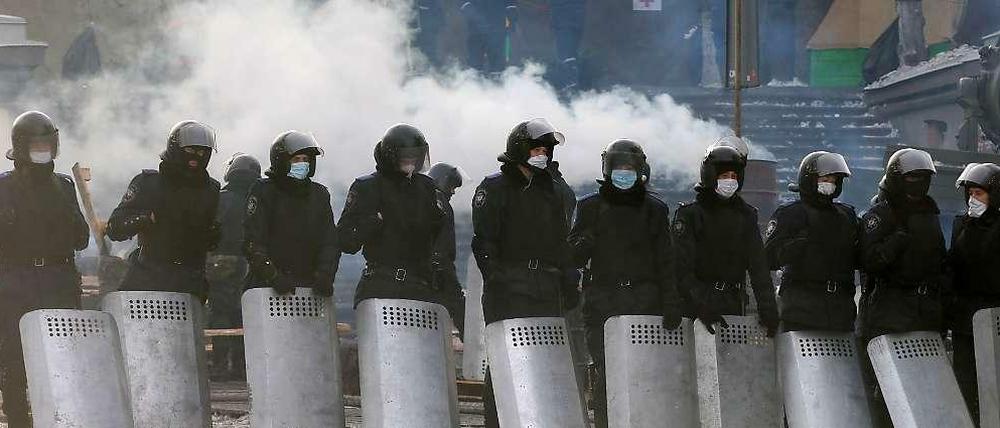Polizisten stehen aufgereiht und beobachten die Demonstranten in Kiew.