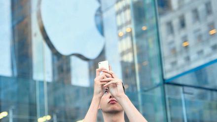 Knipsen bis es passt. Ein Apple-Fan mit seinem neuen iPhone. Es kann bis zu zehn Fotos in der Sekunde schießen. Auf Wunsch sucht es sogar selbst das beste aus. Foto: AFP