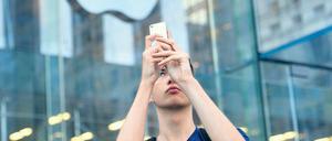 Knipsen bis es passt. Ein Apple-Fan mit seinem neuen iPhone. Es kann bis zu zehn Fotos in der Sekunde schießen. Auf Wunsch sucht es sogar selbst das beste aus. Foto: AFP