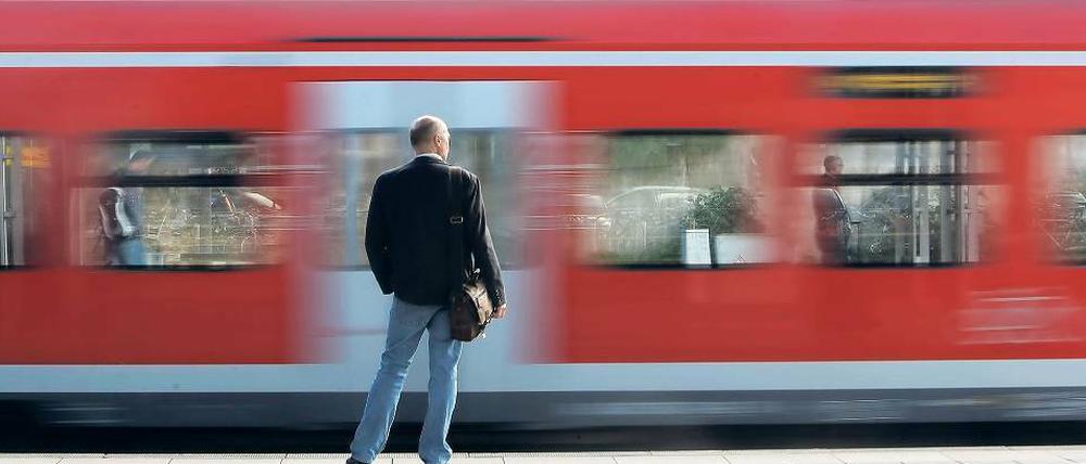 Ein Mann steht an einem Mainzer Bahnsteig, an ihm fährt gerade ein roter Regionalzug vorbei.