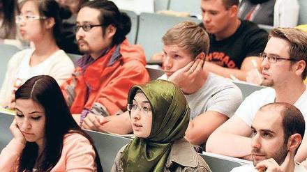 Studierende mit und ohne ausländische Wurzeln sitzen in einem Hörsaal.