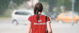 Eine Frau läuft in strömendem Regen in Hannover über die Straße.