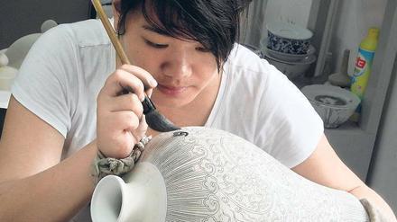 Alles Handarbeit. Einzig ein ruhig geführter Pinsel garantiert absolute Präzision. Porzellanmalerin in einer Manufaktur von Jingdezhen