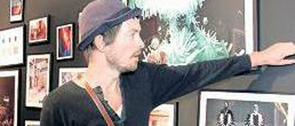 Henrik Vibskov zeigt auf Fotos, auf denen seine Entwürfe zu sehen sind.