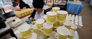 Handarbeit. In Stoke-on-Trent werden die Porzellan-Tassen und -Teller in Manufakturen hergestellt, denen es mit der steigenden Beliebtheit der Königsfamilie derzeit wirtschaftlich wieder besser geht. Sobald der Name des Kindes des Prinzenpaares von Wales bekannt ist, wird er nachgetragen.