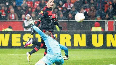 Entscheidung im Schneetreiben. Oscar Cardozo von Benfica Lissabon überwindet Leverkusens Torhüter Bernd Leno nach einer feinen Einzelleistung und schießt das einzige Tor des Spiel. Foto: dpa