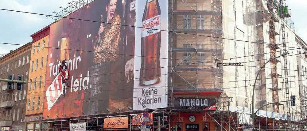 Es werde Licht. Am Mittwoch fotografierten Berliner und Touristen noch die Fassadenkletterer, die den Werbeslogan zur Entschuldigung umklebten. Wegen des Plakates für Coca-Cola hatte Fernando Rossi (o.r.) tagelang eine verhängte Sicht. Noch am gestrigen Abend wollte der Softdrinkkonzern das umstrittene Poster an der Danziger Straße 2 abhängen. Fotos: Georg Moritz