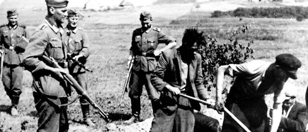 Erzwungen. Wehrmachtssoldaten eines Exekutionskommandos lassen sowjetische Partisanen im Zweiten Weltkrieg ihr eigenes Grab ausheben. An den Massenverbrechen des NS-Regimes in der Sowjetunion waren auch einige Verschwörer des 20. Juli beteiligt.