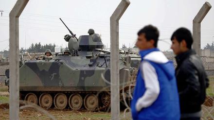 An der syrisch-türkischen Grenze: Syrische Jugendliche beobachten türkische Soldaten durch den Grenzzaun.