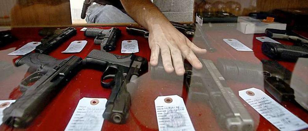Für viele Amerikaner sind Waffen Teil ihrer Identität. Im Bild: Der Verkäufer eines Waffengeschäftes in Wichita, Kansas, greift in einer Auslage nach einer Pistole.
