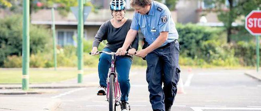 Lenkhilfe. Polizeihauptkommisar Burkhard Poschadel greift ein, damit Hagar Levim die Balance hält. Denn die junge Frau lernt das Radfahren. Foto: Adam Berry/dapd