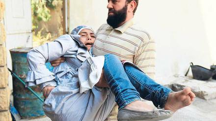 Erste Hilfe: Ein Kämpfer der „Freien Syrischen Armee“ bringt ein verletztes Mädchen in Sicherheit. Hubschrauber und Kampfflugzeuge der Armee bombardieren die nordsyrische Stadt Aleppo, die seit fünf Tagen heftig umkämpft ist.