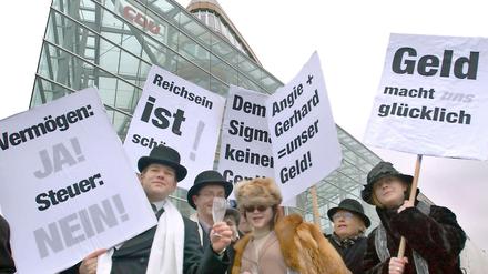 Verkleidet als Millionäre, gehen diese Demonstranten gegen die geplante Vermögenssteuer auf die Straße