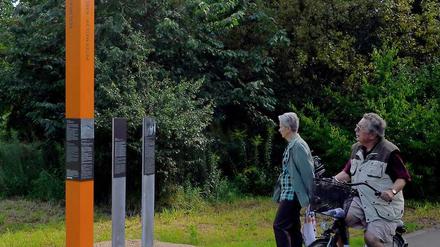 Orangefarbene Stelen erinnern am Mauerweg in Teltow an die Menschen, die bei Fluchtversuchen entlang der Mauer erschossen wurden.