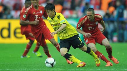 Die Bundesliga-Spieler sehen meistens nur die Hacken von Shiji Kagawa, wie hier die Bayern-Akteure Luiz Gustavo und Frank Ribery. Demnächst können sich Premiere League-Verteidiger mit dem Japaner rumplagen.
