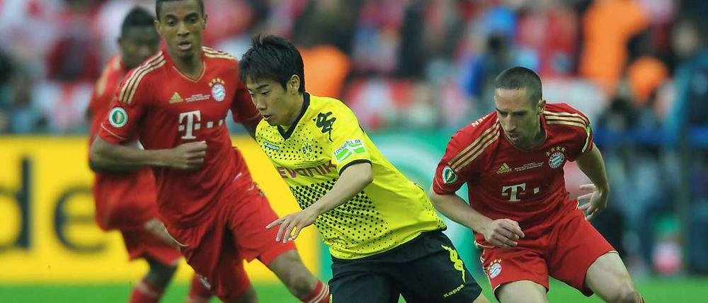 Die Bundesliga-Spieler sehen meistens nur die Hacken von Shiji Kagawa, wie hier die Bayern-Akteure Luiz Gustavo und Frank Ribery. Demnächst können sich Premiere League-Verteidiger mit dem Japaner rumplagen.