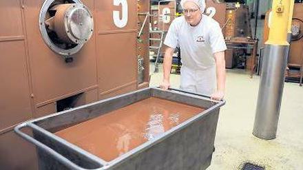 Tonnenweise feine Speise. Ein Mitarbeiter des Bremer „Chocolatiers“ Hachez schiebt eine Wanne geschmolzener Schokolade durchs Werk, das der Investor erhalten will. Foto: dpa