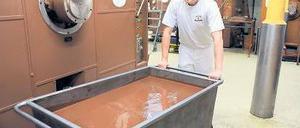 Tonnenweise feine Speise. Ein Mitarbeiter des Bremer „Chocolatiers“ Hachez schiebt eine Wanne geschmolzener Schokolade durchs Werk, das der Investor erhalten will. Foto: dpa