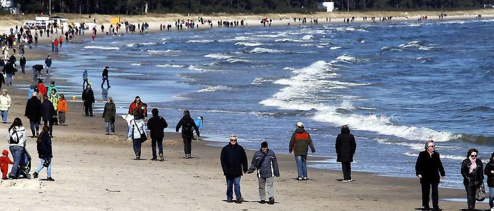 Urlauber spazieren über den Ostseestrand in Binz.