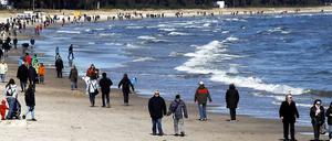 Urlauber spazieren über den Ostseestrand in Binz.