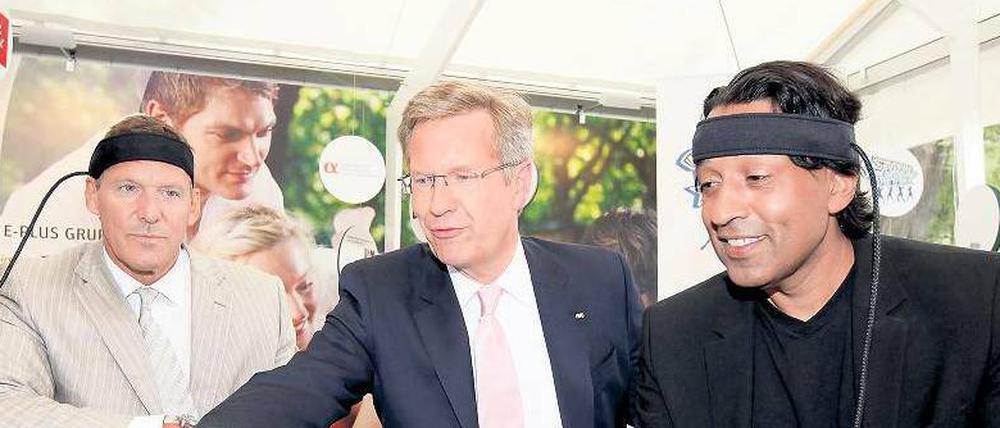 Am grünen Tisch des Sponsors. Ex-Bundespräsident Christian Wulff vergnügte sich 2011 beim Sommerfest im Schloss Bellevue am Stand des Mobilfunkunternehmens E-Plus mit Schauspieler Ralf Möller (l.) und Moderator Cherno Jobatey.