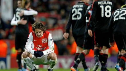 Arsenals Tomas Rosicky kniet am Boden, während sich Mailands Spieler nach dem Spiel umarmen. Wieder ist Rosickys Team im Achtelfinale gescheitert.
