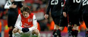 Arsenals Tomas Rosicky kniet am Boden, während sich Mailands Spieler nach dem Spiel umarmen. Wieder ist Rosickys Team im Achtelfinale gescheitert.