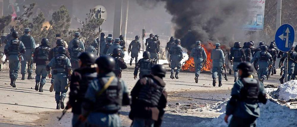 Afghanische Polizisten laufen nahe einer US-Militärbasis in Kabul den Demonstranten entgegen. Autos wurden abgezündet, mehrere Menschen wurden verletzt.