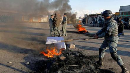 Ein Polizeibeamter in Kabul verbrennt eine Flagge der Taliban. 