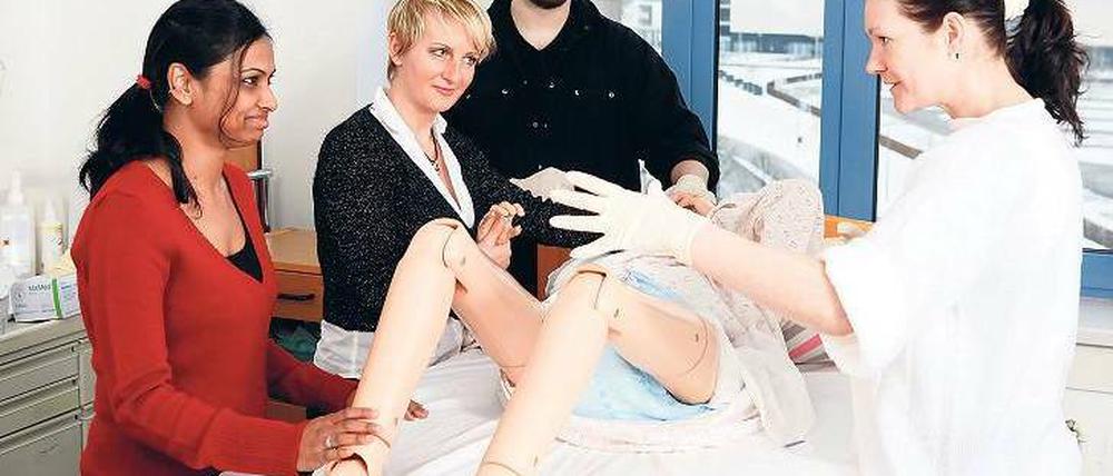Lernen am Modell. Lipi Akter, Dubravka Sormaz, André Mevius und Katrin Krohn (von links) üben an einer Puppe den Umgang mit pflegebedürftigen Menschen. Foto: Georg Moritz