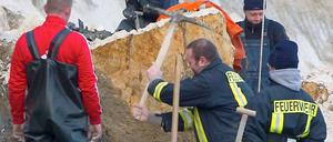 Einsatzkräfte der Feuerwehr durchsuchen das Geröll an der Unglücksstelle.