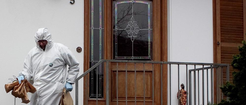 Ein Mitarbeiter der Spurensicherung trägt Papiertüten aus dem Wohnhaus des 49-jährigen Polizisten.